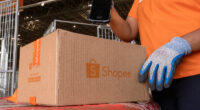 Funcionário da Shopee realiza leitura de pacote em centro logístico, destacando operação de entregas rápidas em Minas Gerais