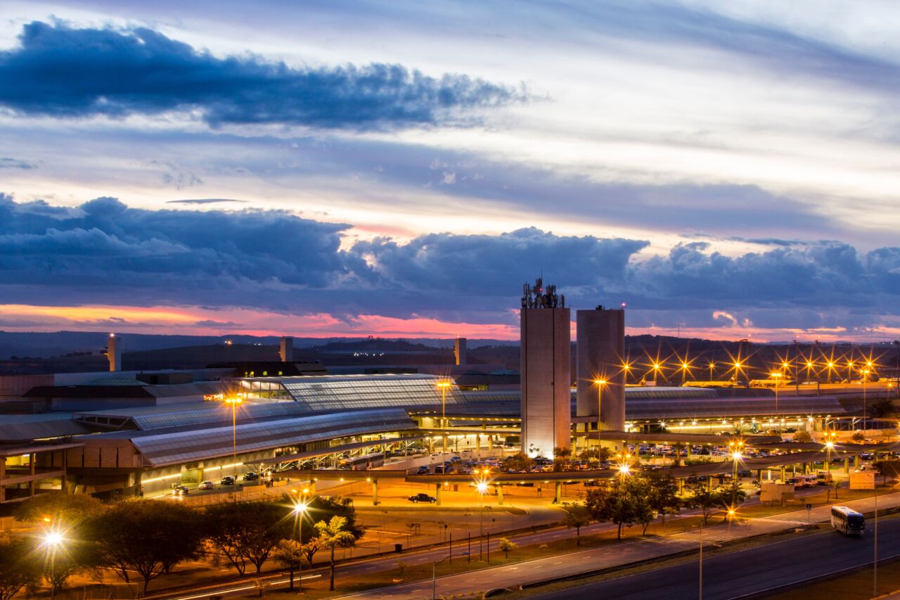 BH Airport amplia malha aérea e conectividade nacional Vista aérea do BH Airport ao entardecer, com terminal iluminado e estrutura aeroportuária na Região Metropolitana de Belo Horizonte