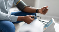 Pessoa medindo a pressão arterial com aparelho digital em casa, ilustrando prevenção e controle da hipertensão