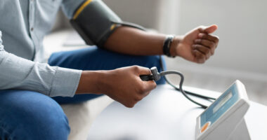 Pessoa medindo a pressão arterial com aparelho digital em casa, ilustrando prevenção e controle da hipertensão