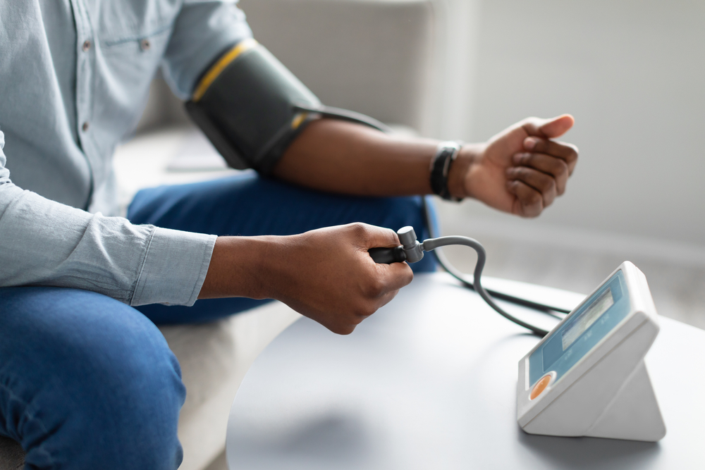 Pessoa medindo a pressão arterial com aparelho digital em casa, ilustrando prevenção e controle da hipertensão