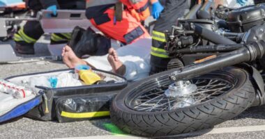 Motocicleta caída na pista enquanto socorristas atendem vítima de acidente de trânsito, ilustrando alta de ocorrências com motos atendidas no João XXIII