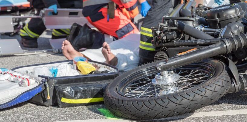 Acidente com motociclista mobiliza socorristas após colisão no trânsito Motocicleta caída na pista enquanto socorristas atendem vítima de acidente de trânsito, ilustrando alta de ocorrências com motos atendidas no João XXIII