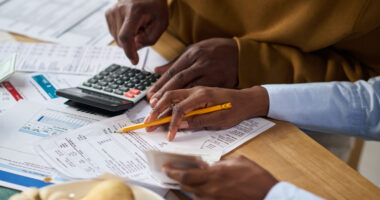 Pessoas analisam contas e utilizam calculadora durante organização financeira doméstica, em imagem que representa o aumento do endividamento das famílias em Belo Horizonte