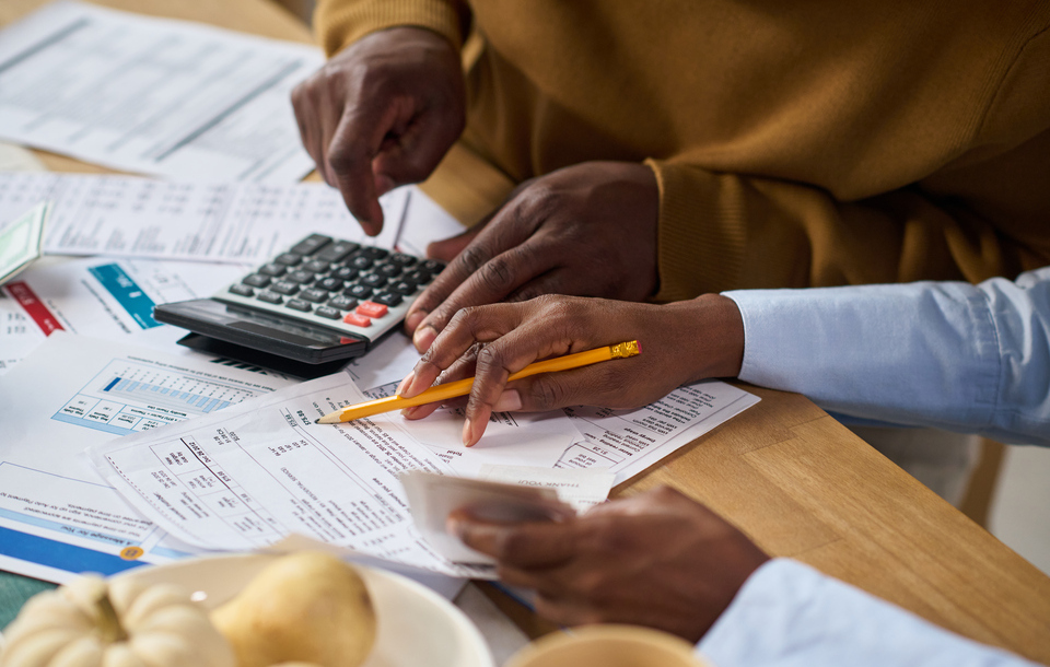 Famílias de BH enfrentam alto endividamento em cenário de juros elevados Pessoas analisam contas e utilizam calculadora durante organização financeira doméstica, em imagem que representa o aumento do endividamento das famílias em Belo Horizonte