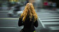 Pedestre próxima à faixa de travessia em área urbana, reforçando alerta sobre segurança no trânsito e atenção ao atravessar ruas