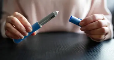 Pessoa segura caneta emagrecedora utilizada no tratamento da obesidade, em imagem que ilustra o processo de desmame e manutenção do peso após o uso de medicamentos como Ozempic e Mounjaro