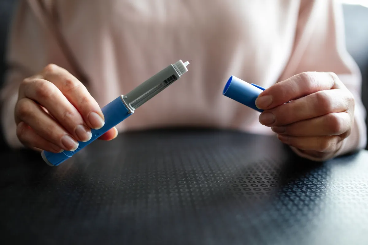 Desmame das canetas emagrecedoras exige acompanhamento para manutenção dos resultados Pessoa segura caneta emagrecedora utilizada no tratamento da obesidade, em imagem que ilustra o processo de desmame e manutenção do peso após o uso de medicamentos como Ozempic e Mounjaro