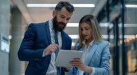 Profissionais analisam dados em dispositivo digital durante processo de gestão contratual com uso de inteligência artificial