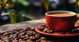 Xícara de café sobre mesa cercada por grãos torrados, imagem que representa o crescimento da produção cafeeira em Minas Gerais e o avanço do consumo da bebida entre jovens