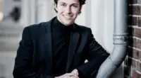 Pianista holandês Nikola Meeuwsen posa de blazer preto e gola alta preta em retrato fotográfico antes da estreia na Orquestra Filarmônica de Minas Gerais