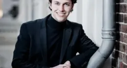 Pianista holandês Nikola Meeuwsen posa de blazer preto e gola alta preta em retrato fotográfico antes da estreia na Orquestra Filarmônica de Minas Gerais