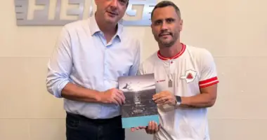 Flávio Roscoe e Cleitinho Azevedo na sede da Fiemg e seguram juntos um documento impresso do Pacto por Minas 2026 sobre as prioridades para a indústria no estado